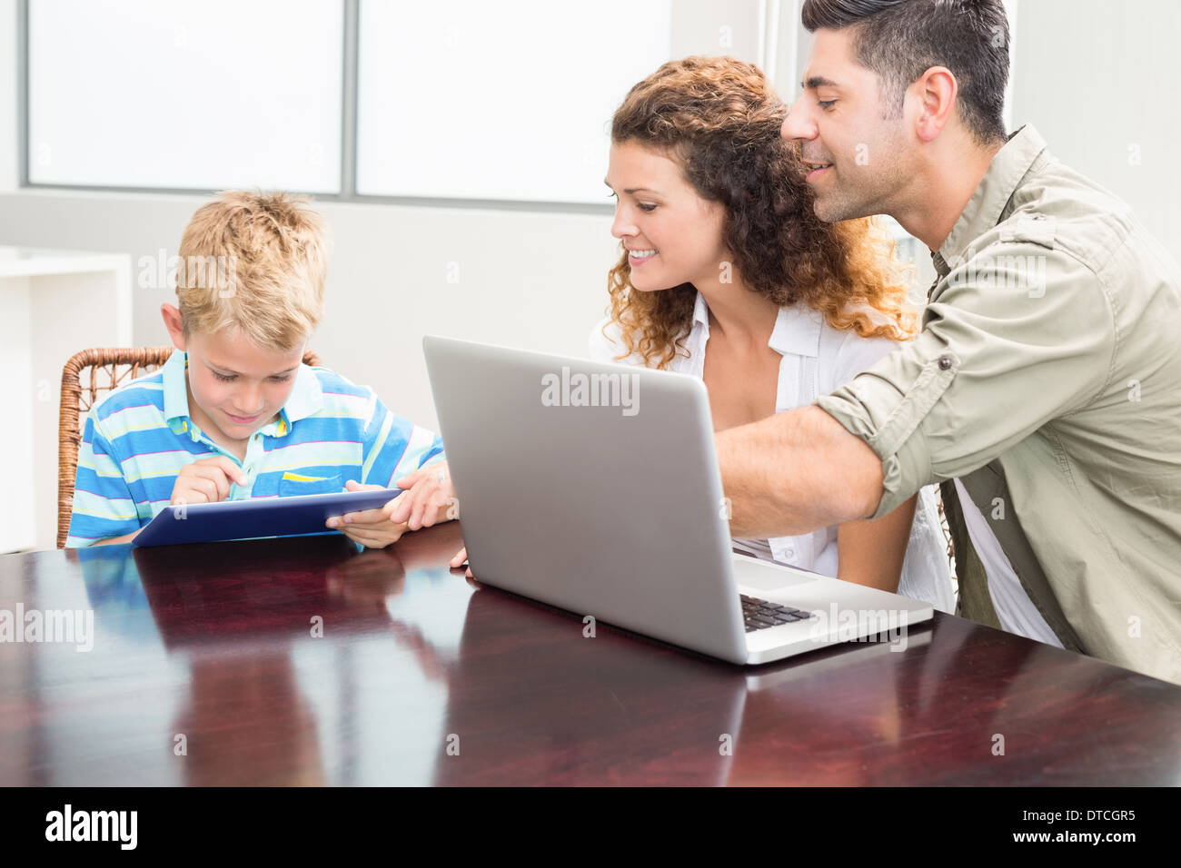 Genitori felici figlio che mostra come utilizzare il tablet pc Foto Stock