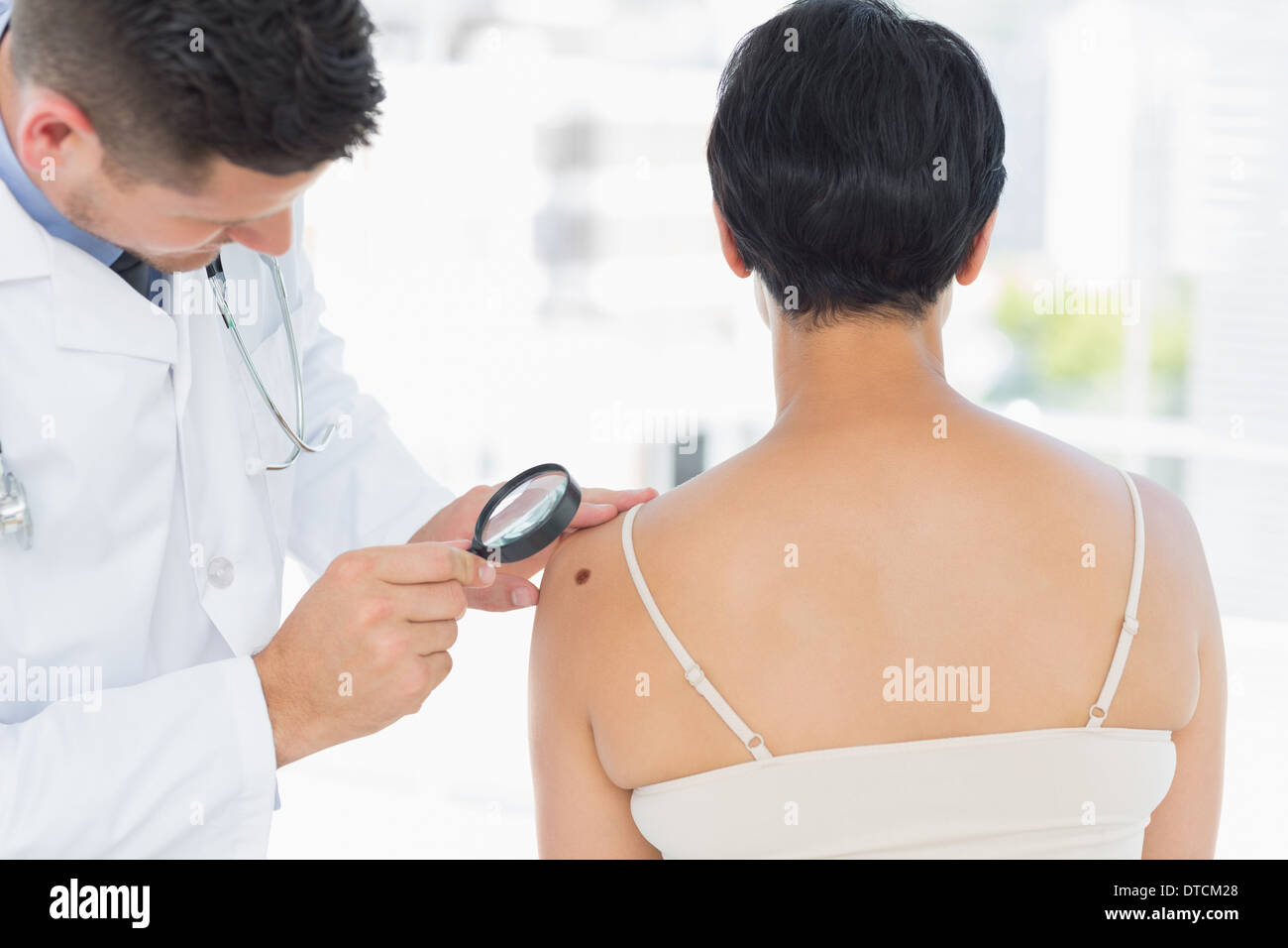 Il dermatologo esaminando il melanoma sulla donna Foto Stock