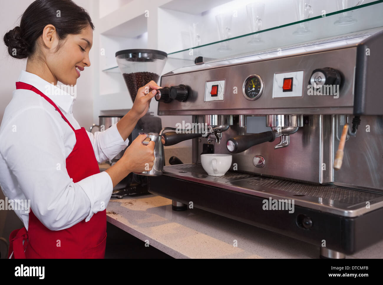 Piuttosto barista caraffa fumante di latte alla macchina per il caffè Foto Stock