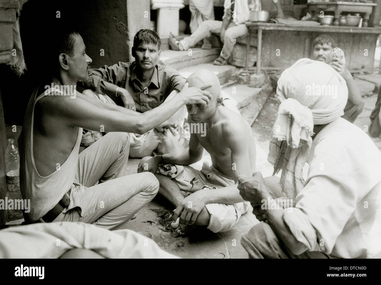 Funerale rituale taglio di capelli alla cremazione Manikarnika ghat Varanasi Benares in Uttar Pradesh in India in Asia del Sud. Il taglio dei capelli morte Fiume Gange Travel Foto Stock