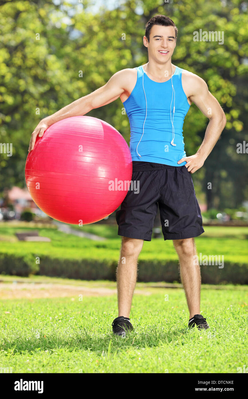 Bello atleta maschio in posa di parco con una sfera di pilates Foto Stock