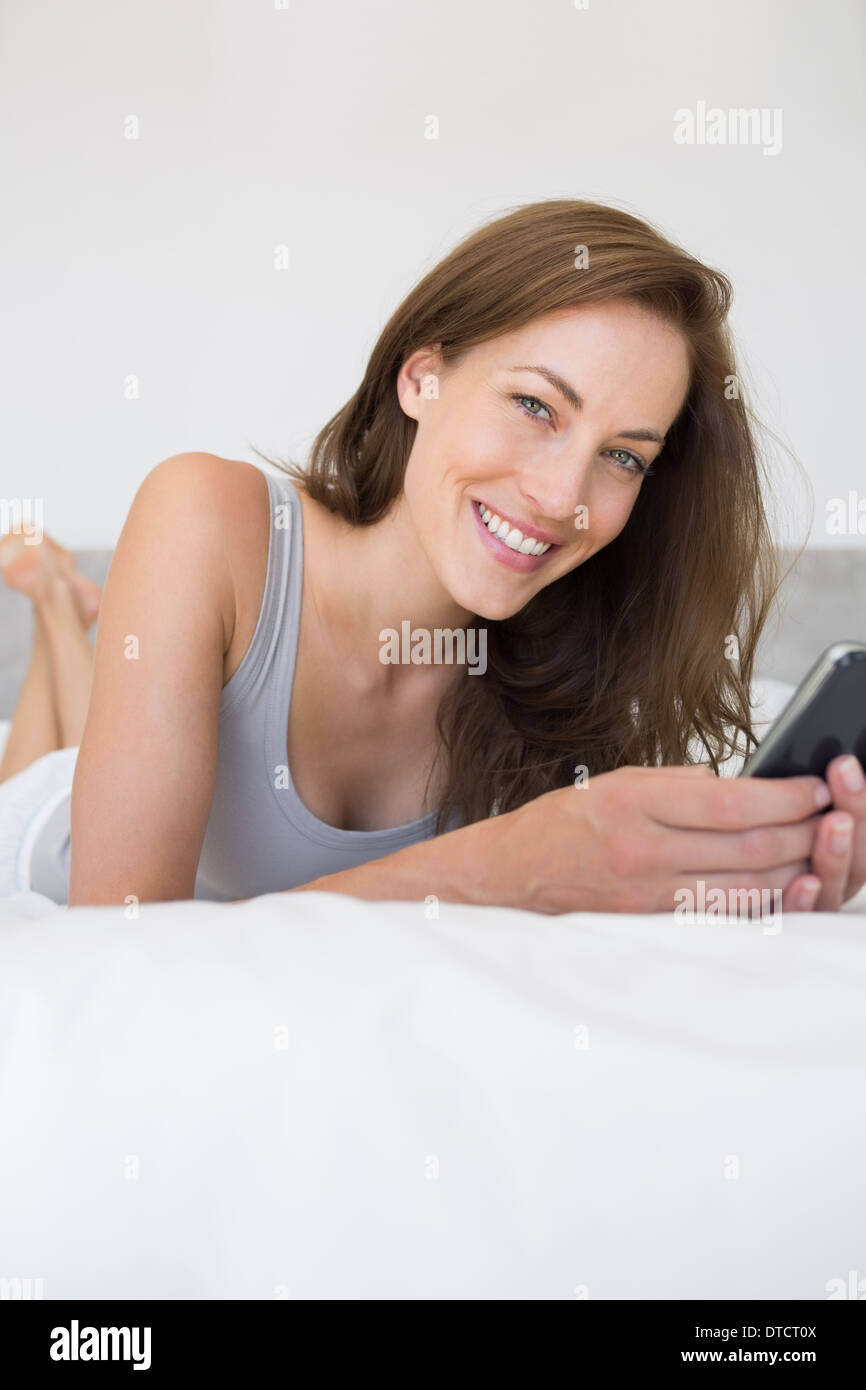 Abbastanza rilassato donna alla messaggistica di testo nel letto Foto Stock