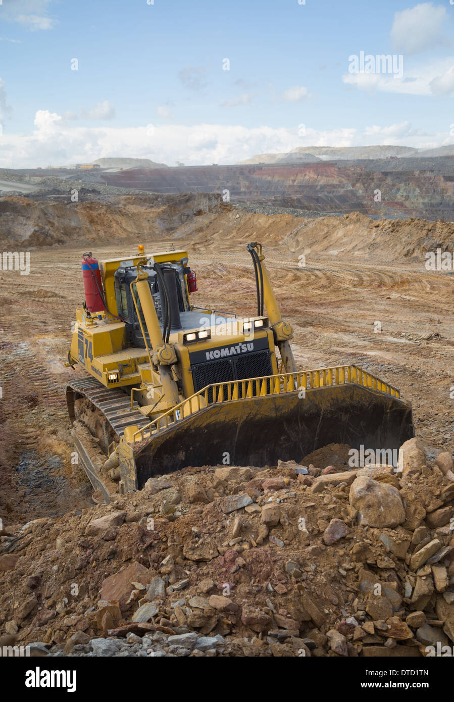 Un massiccio giallo komatsu bulldozer spinge rifiuti rock e terreno in un grande cast aperto di rame e di golf miniera in Zambia, Africa. Foto Stock