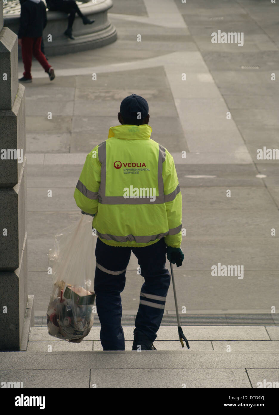 Un lavoratore del consiglio la raccolta di rifiuti in un sacchetto con un prelevamento griffa in Trafalgar Square, Londra Foto Stock