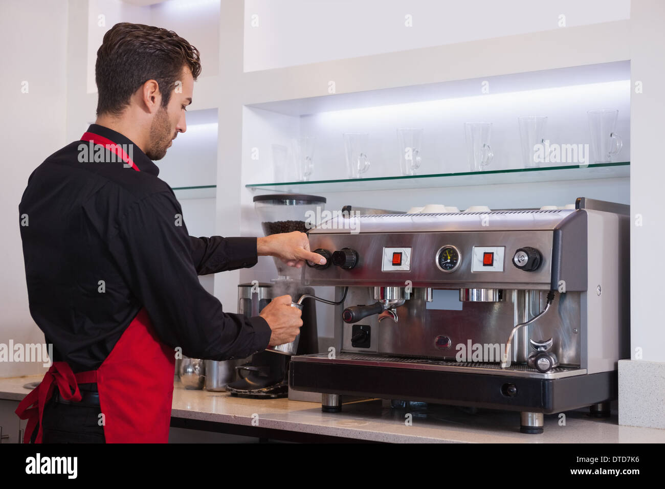 Bel giovane barista fumante brocca del latte Foto Stock