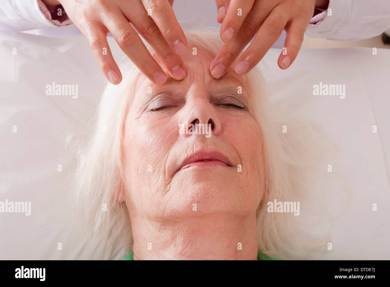 Donna matura la ricezione di digitopressione come parte del trattamento acutherapy Foto Stock