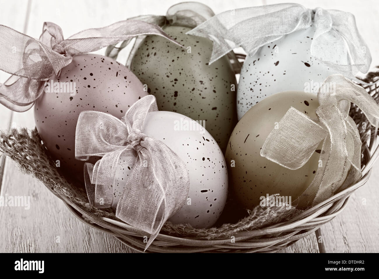Uova di Pasqua in un cesto su sfondo di legno Foto Stock