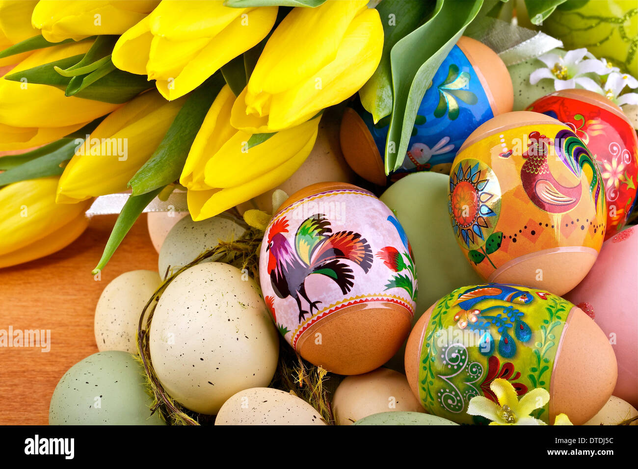Uova di Pasqua e tulipani gialli su sfondo di legno Foto Stock