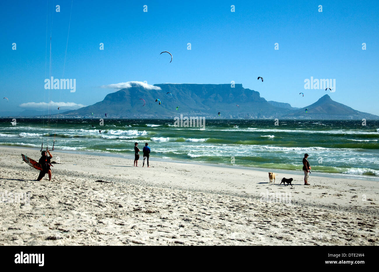Cape Town iconici Table Mountain visto da Blouberg Strand. Kiteboards adornano il cielo e la gente rilassata sulla spiaggia. Foto Stock