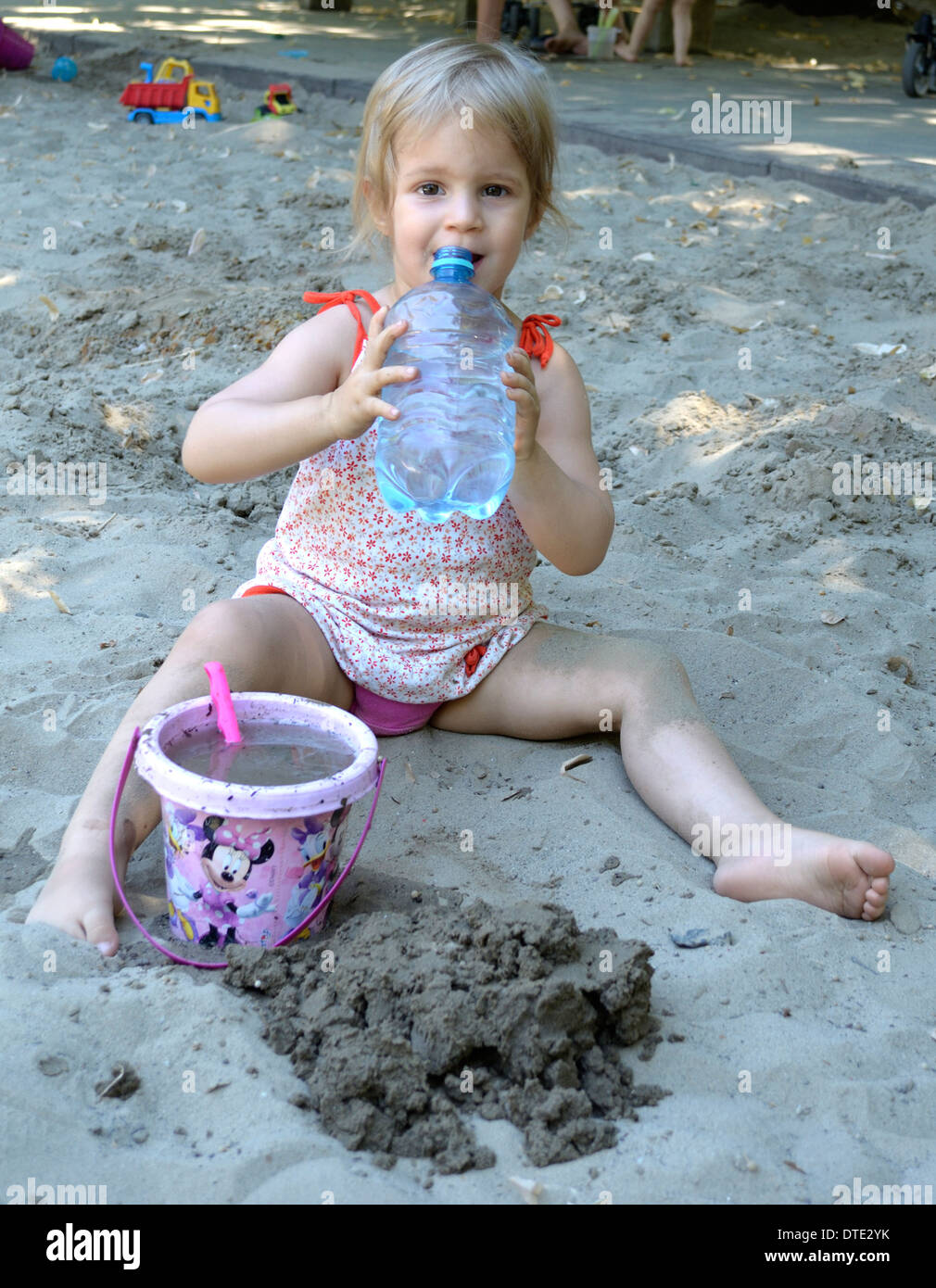 Bambina 3 anni acqua bevande presso il parco giochi Foto Stock