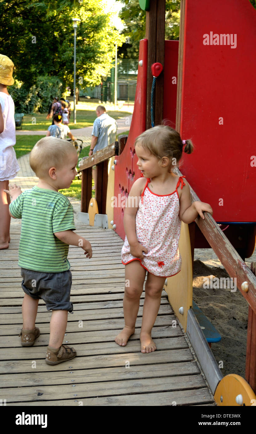 Bambina e ragazzo incontro a vicenda sul parco giochi Foto Stock