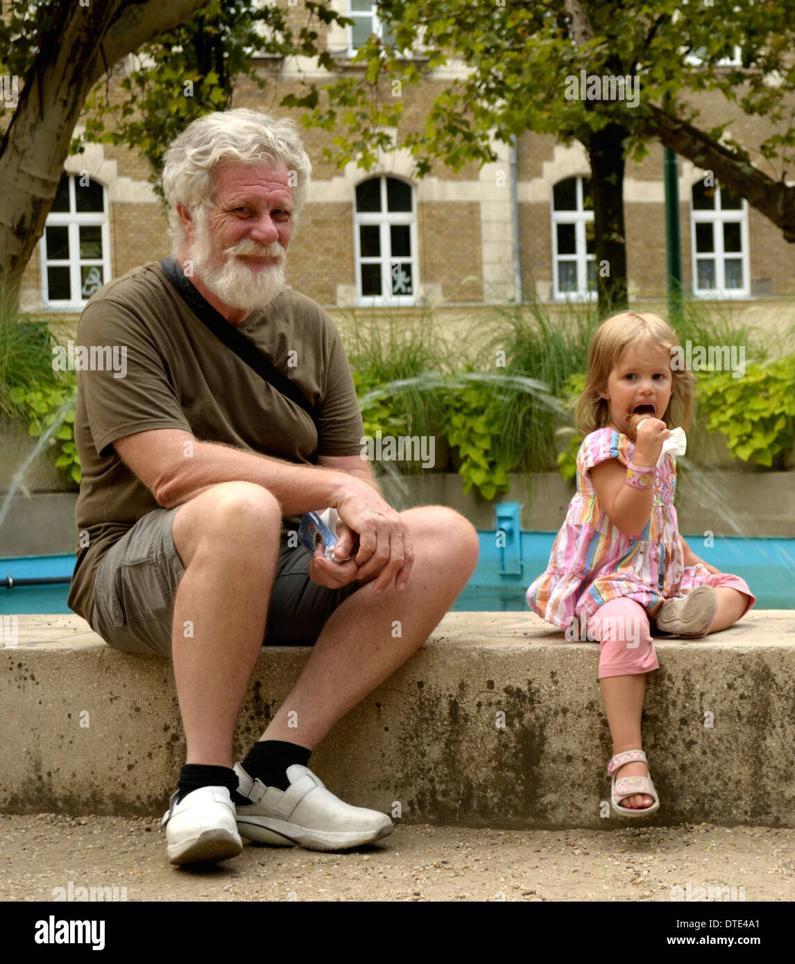 Bambina leccare il gelato nel parco con il nonno Foto Stock