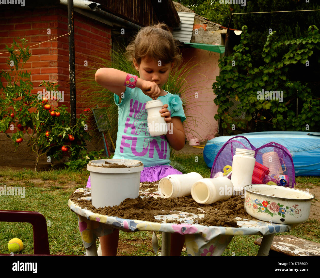 Bambina gioca con la sabbia sul tavolo da giardino Foto Stock