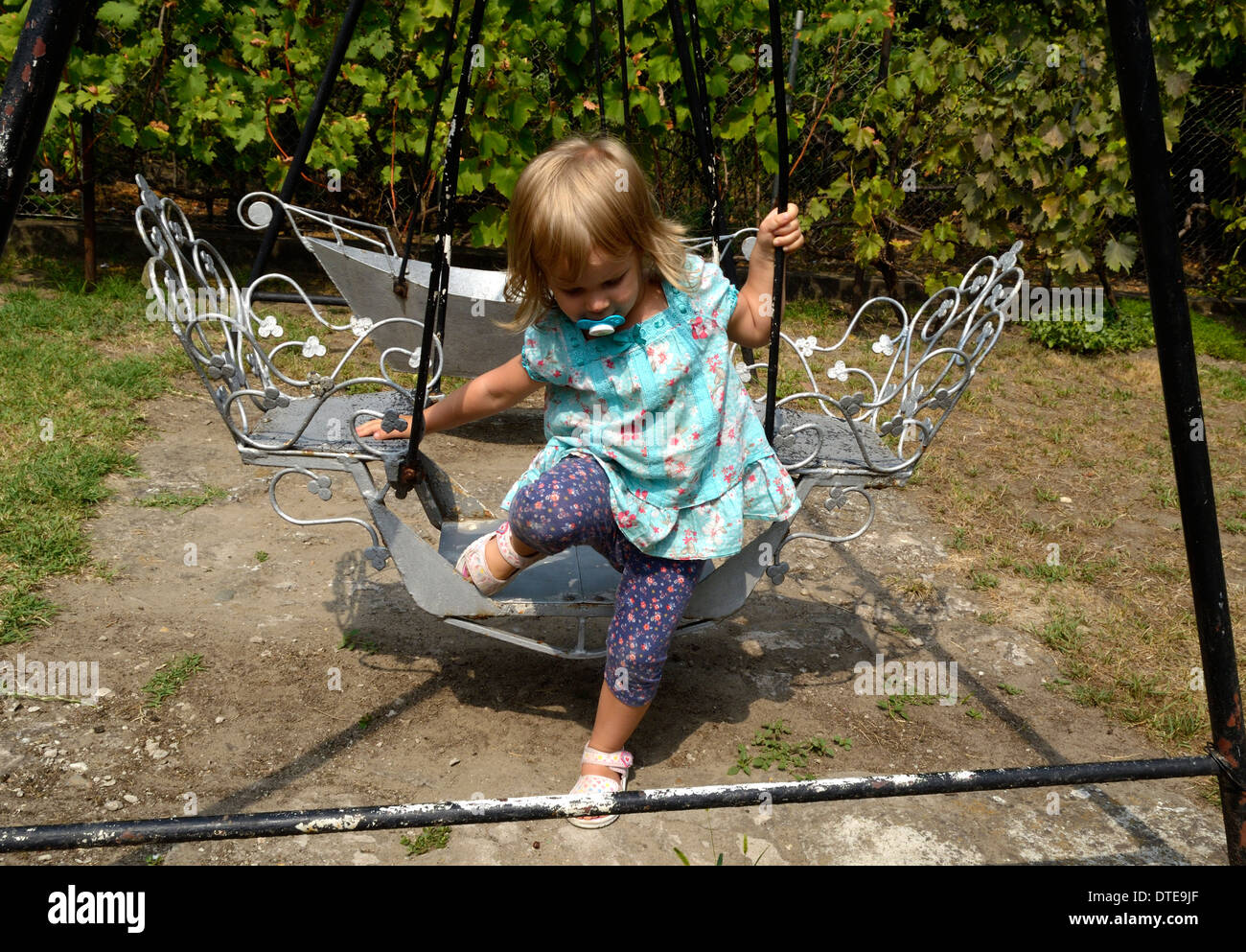 Bambina sull'altalena in vestito blu Foto Stock