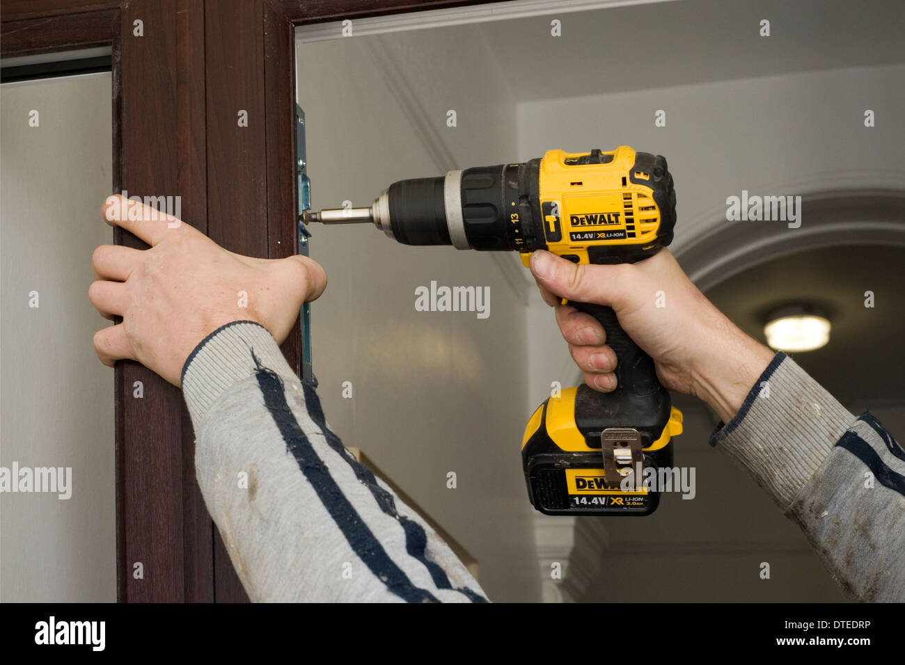 Tradesman all'opera per preparare una nuova porta e il telaio di montaggio sulla parte anteriore di un ambiente domestico Foto Stock