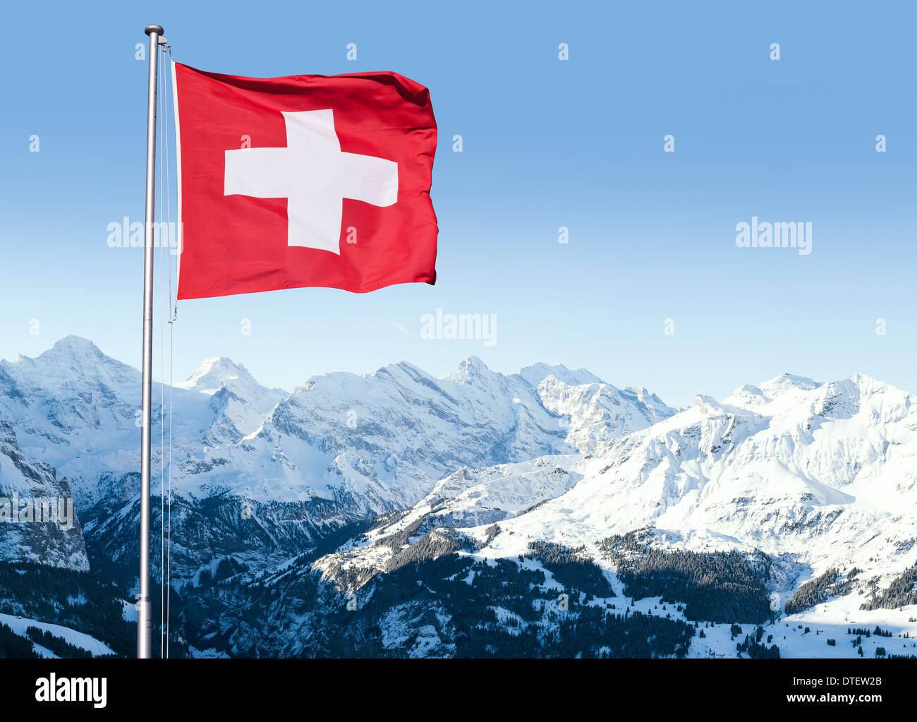 Bandiera della Svizzera che fluttua nel vento con le alpi Bernesi in background, Grindelwald, Svizzera. Foto Stock
