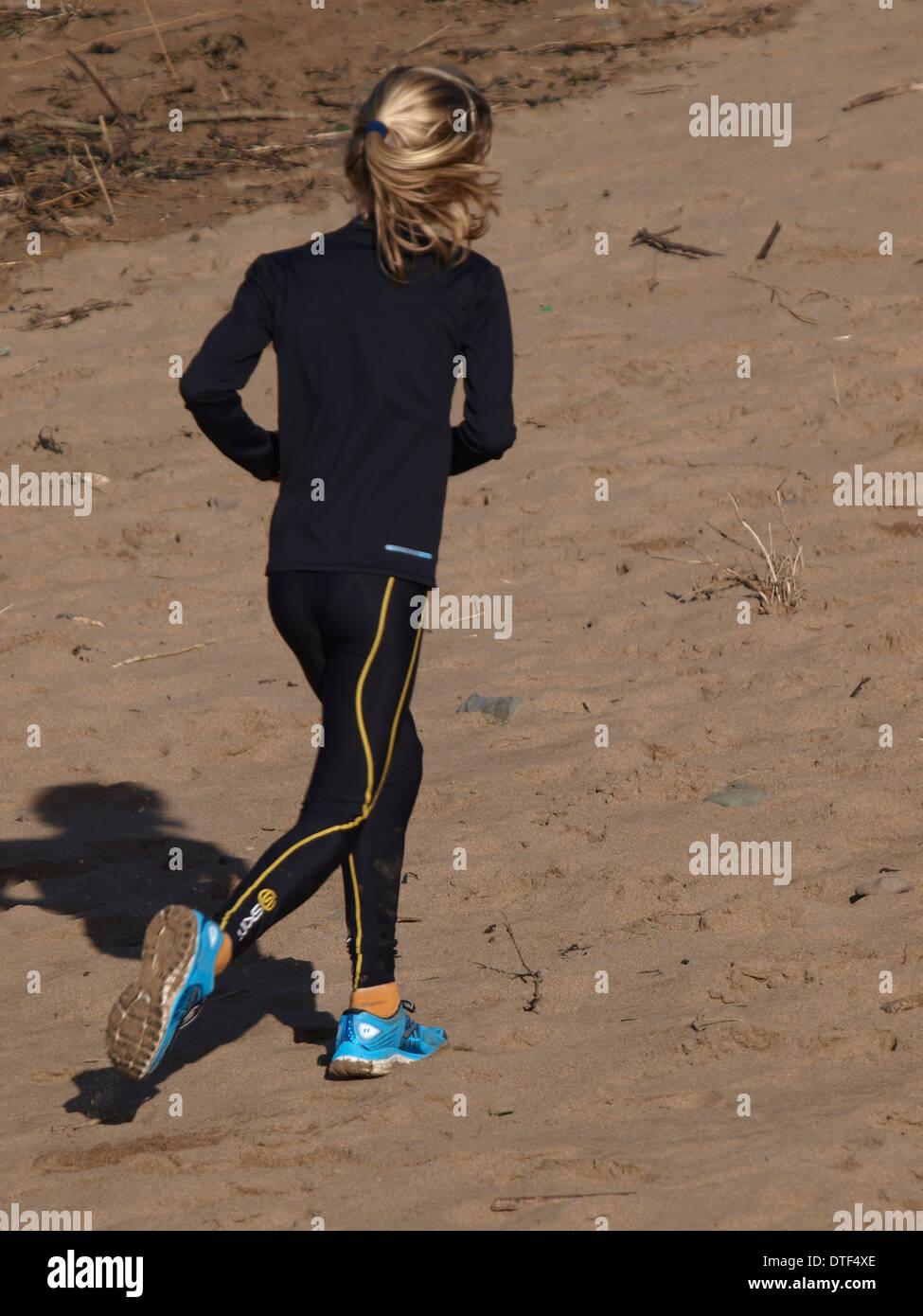 Ragazza giovane jogging lungo la spiaggia, Bude, Cornwall, Regno Unito Foto Stock