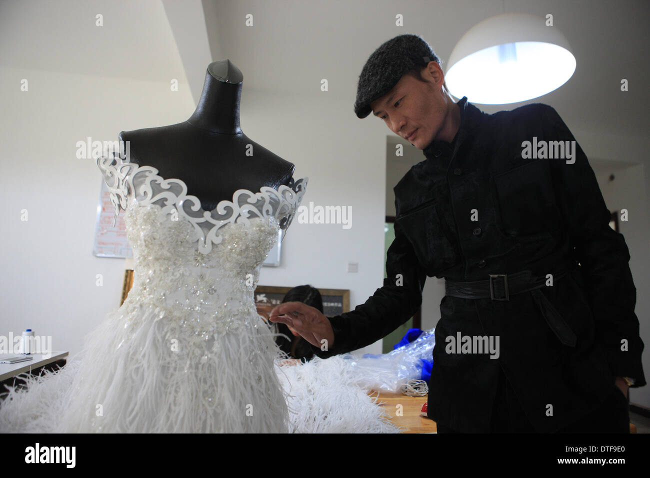 Pechino, Cina. 17 feb 2014. Designer Laurence Xu controlli un incompiuto bespoke abito da sposa nel suo studio di Pechino, capitale della Cina, Feb 17, 2014. Xu, un, Shandong Cina-NATO, Parigi-basato designer, che mostrerà le sue nuove creazioni alla settimana della moda di Parigi nel mese di luglio. Credito: Liu Changlong/Xinhua/Alamy Live News Foto Stock