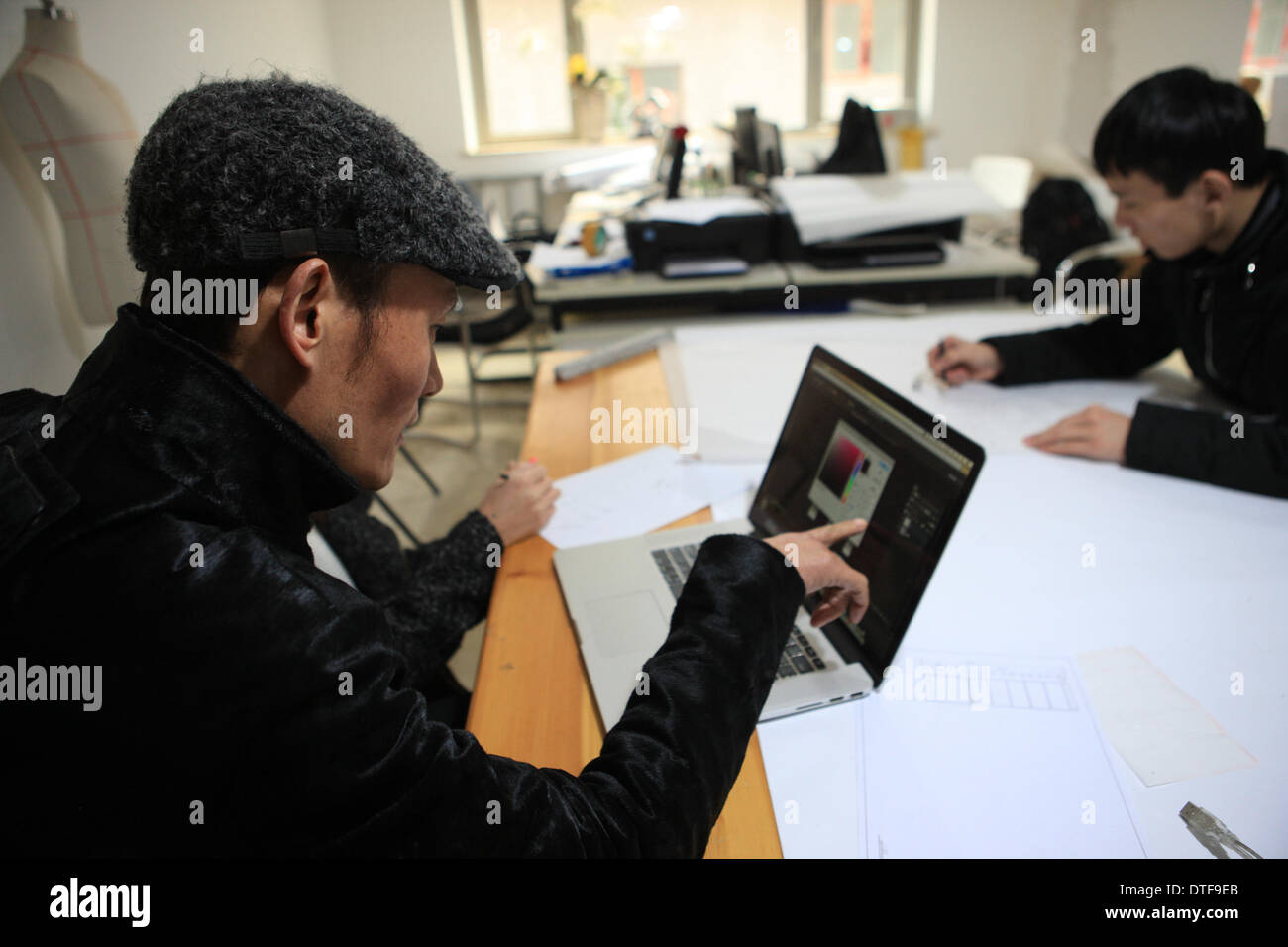 Pechino, Cina. 17 feb 2014. Designer Laurence Xu (L) discute le sue creazioni nel suo studio di Pechino, capitale della Cina, Feb 17, 2014. Xu, un, Shandong Cina-NATO, Parigi-basato designer, che mostrerà le sue nuove creazioni alla settimana della moda di Parigi nel mese di luglio. Credito: Liu Changlong/Xinhua/Alamy Live News Foto Stock