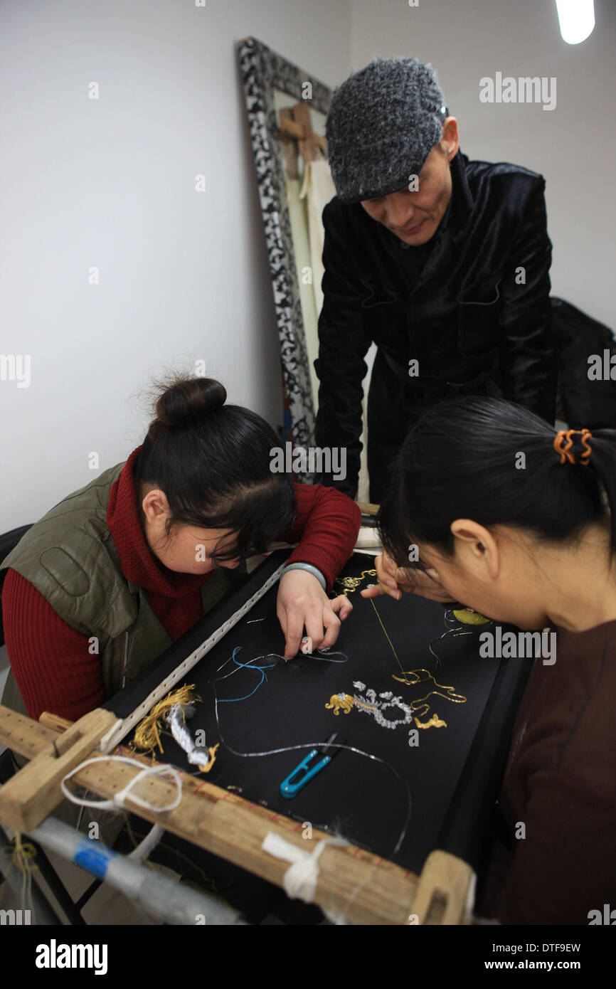 Pechino, Cina. 17 feb 2014. Designer Laurence Xu (C) controlla la realizzazione di un ricamo nel suo studio di Pechino, capitale della Cina, Feb 17, 2014. Xu, un, Shandong Cina-NATO, Parigi-basato designer, che mostrerà le sue nuove creazioni alla settimana della moda di Parigi nel mese di luglio. Credito: Liu Changlong/Xinhua/Alamy Live News Foto Stock