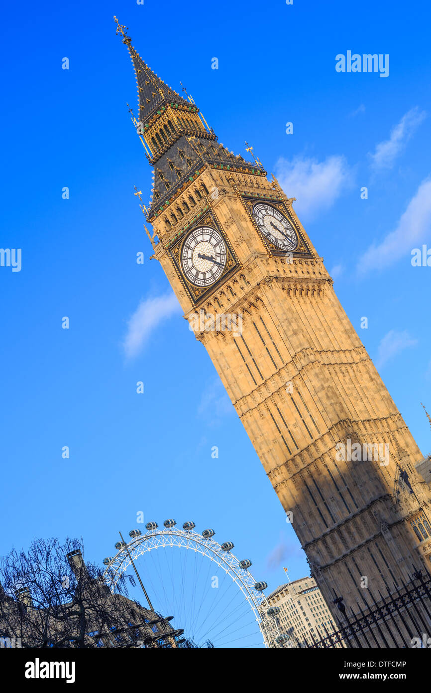 Il Big Ben e la torre orologio al Palazzo di Westminster a Londra. Torre shot contro un cielo blu chiaro. London eye a posteriori. Foto Stock