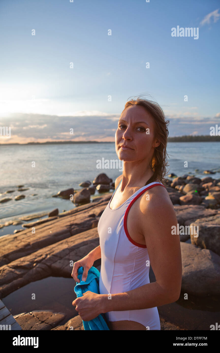 Donna attraente in bianco costume da bagno al mare roccioso nel paese nordico durante l'estate Foto Stock