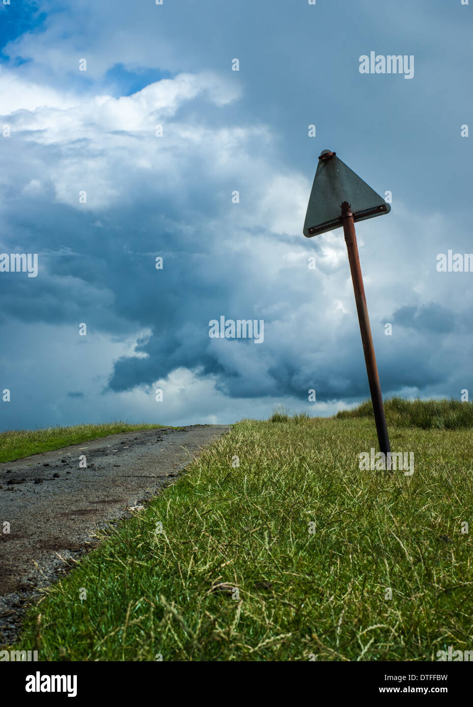 Rotture di cartello stradale da un vicolo del paese sotto un cielo tempestoso Foto Stock