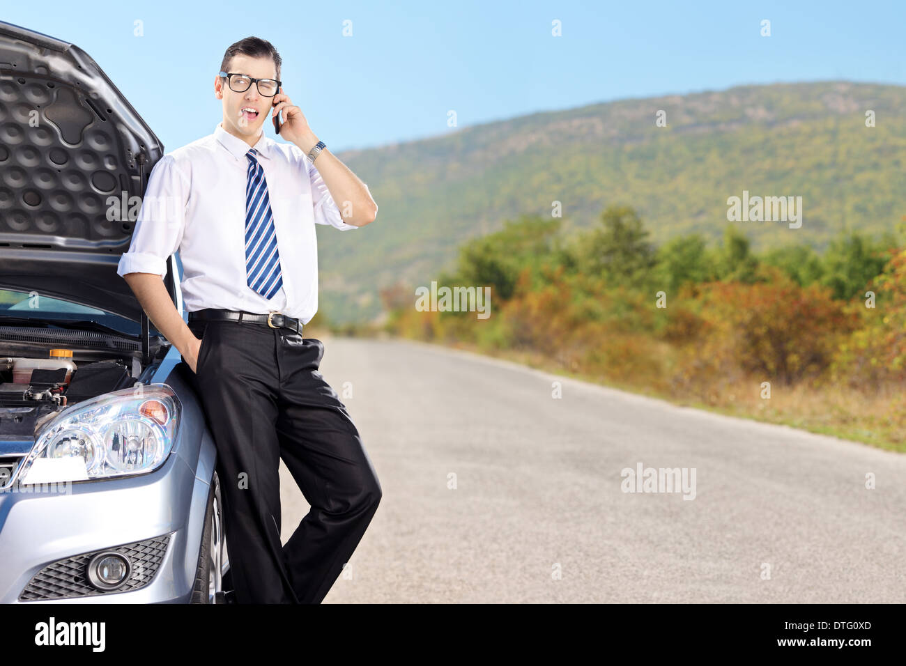 Imprenditore parlando al telefono cellulare e seduto su una macchina Foto Stock