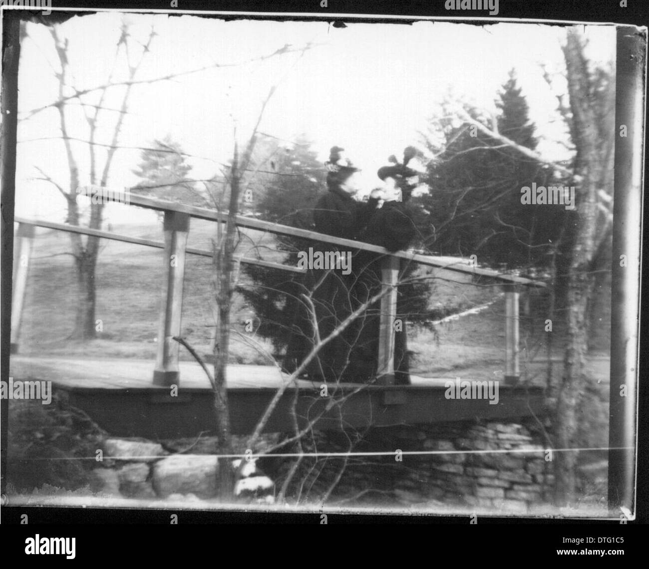 Una fotografia che mostra tre donne su un ponte al Western College Pond, catturando un momento di vita sociale all'inizio del XX secolo alla Miami University. Questa immagine evidenzia l'importanza dell'educazione femminile e le dinamiche sociali del tempo a Oxford, Ohio. Foto Stock