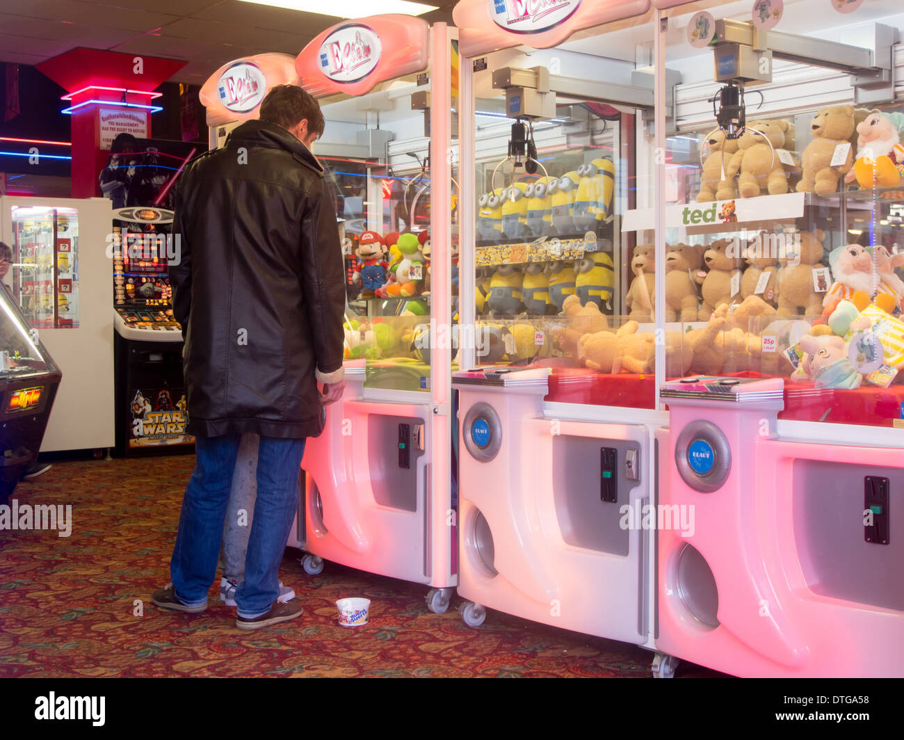 Uomo che guarda un grab macchina in un tipico inglese lato mare divertimento arcade Foto Stock