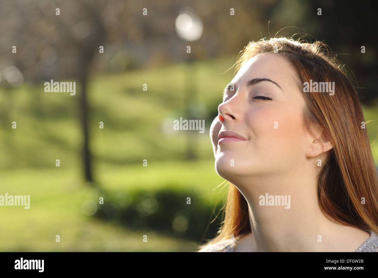 Ritratto di una donna rilassata respirazione profonda in un parco con un calore di sfondo retroilluminato e Foto Stock