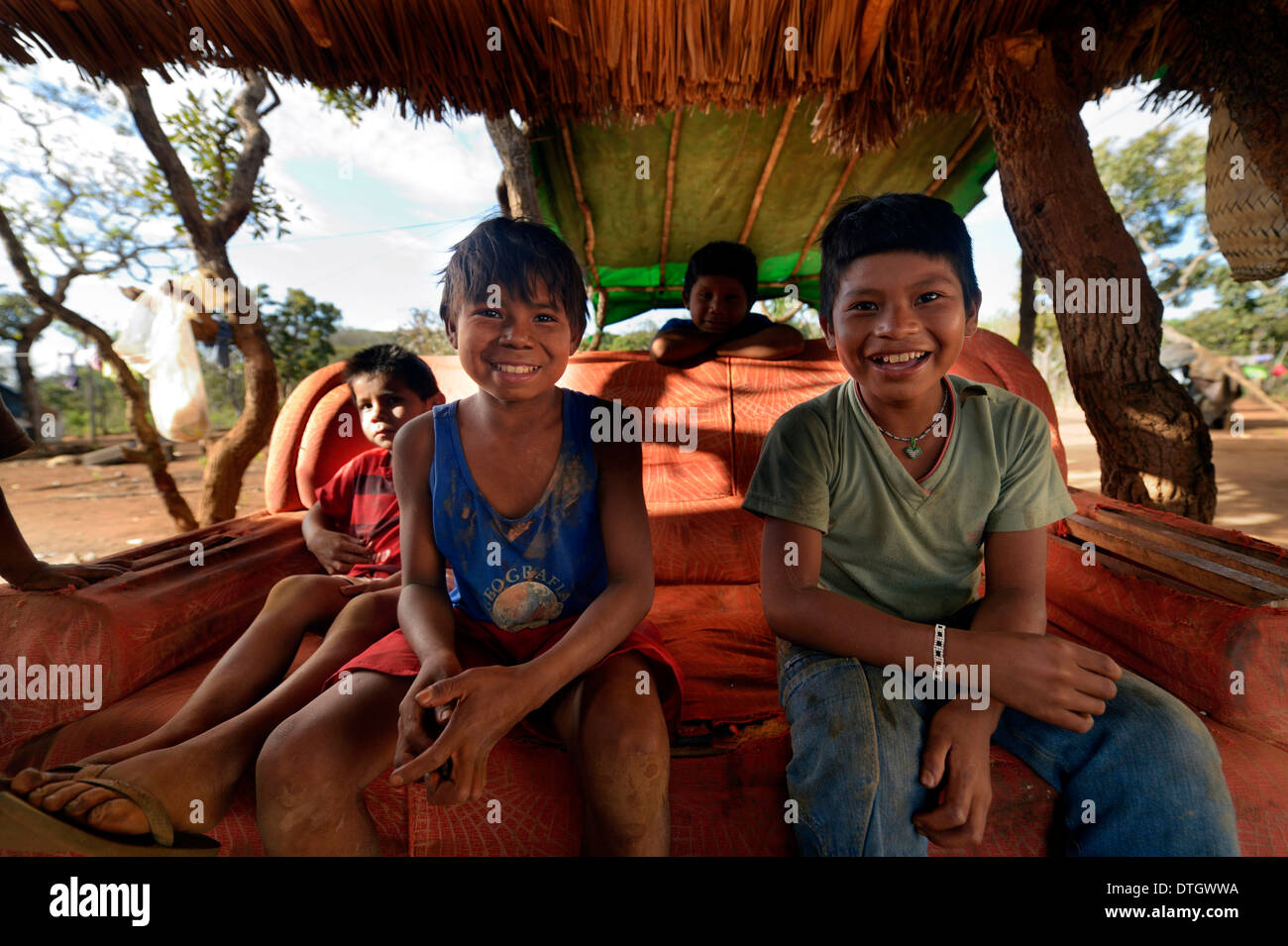 Bambini indigeni seduti su un vecchio divano in ombra, nel villaggio del popolo Xavantes, Tres Rios vicino alla missione di Foto Stock