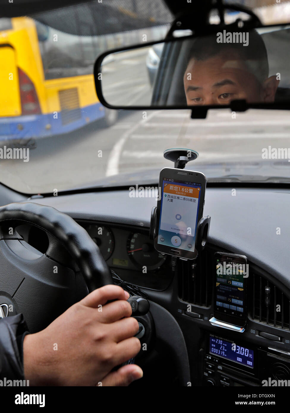 (140218) -- PECHINO, febbraio 18, 2014 (Xinhua) -- un taxi driver utilizzare entrambi Didi e KuaiDi, cabina-salutando le app su due smartphone per trovare più clienti a Pechino Capitale della Cina, Feb 18, 2014. Alipay, il paese più grande del pagamento in linea di terze parti di piattaforma e una filiale del gruppo Alibaba, ha fortemente investito nella cabina-salutando app KuaiDi sul pagamento di sovvenzioni per promuovere il suo servizio di pagamento online. Il passaggio è venuto sulla scia di un simile programma di sovvenzione da cab-salutando app Didi, con investimento di Tencent. Didi è stimolante, ha annunciato i primi di gennaio, incoraggia i passeggeri a pagare le tariffe dei taxi via ten Foto Stock