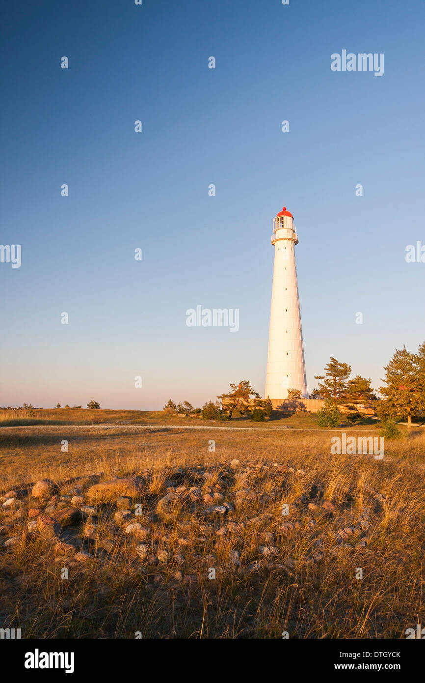 Tall slim bianco o faro faro noto come Tahkuna al tramonto in Hiiumaa, Estonia e labirinto di pietra o labirinto in primo piano. Foto Stock