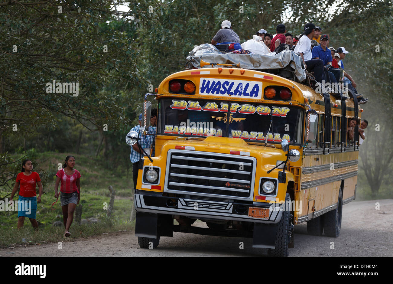 Persone a cavallo sul tetto di un autobus gialli, Rio Blanco, Nicaragua Foto Stock