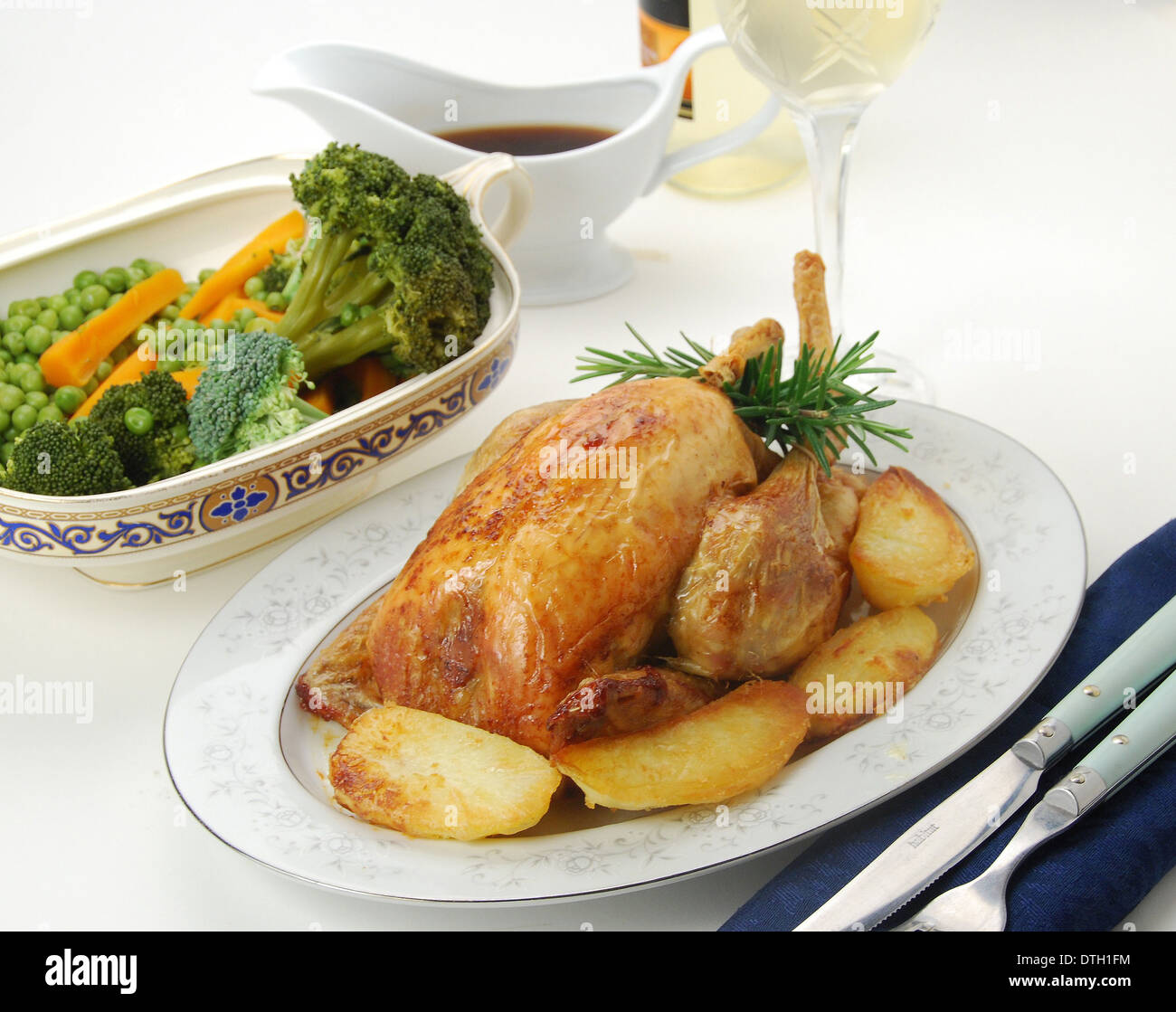 Arrosto Domenicale. Forno pollo arrosto con golden patate arrosto, verdure miste, con sugo di carne e un bicchiere di vino bianco Foto Stock