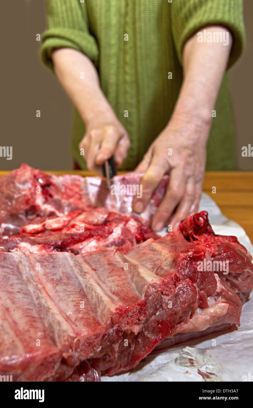 Mani il taglio di carne di maiale e osso. Messa a fuoco selettiva con profondità di campo ridotta. Foto Stock