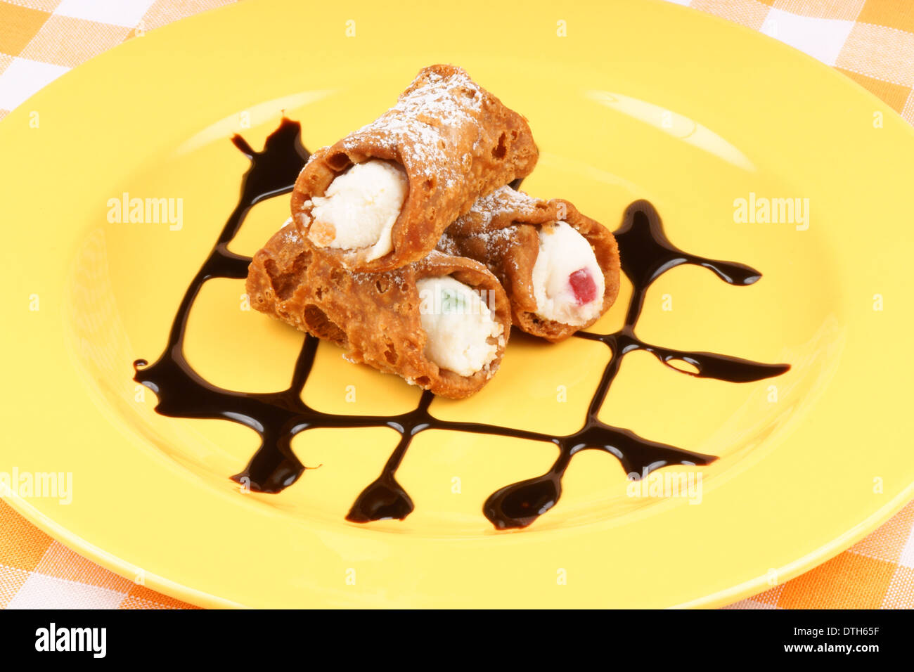 Alcuni originali mini cannoli siciliani su una piastra di colore giallo. Foto Stock