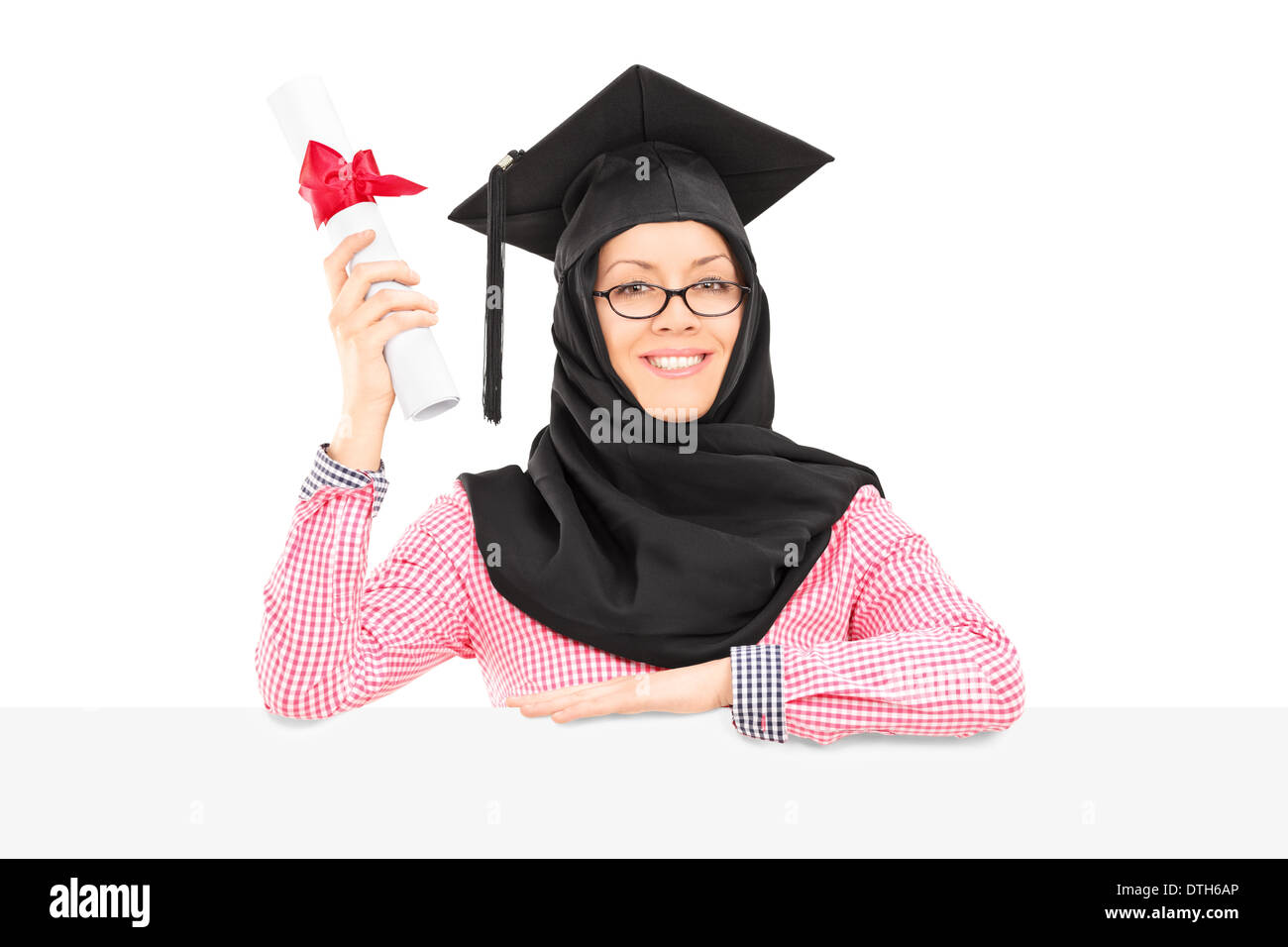 Femmina studente islamico con mortarboard e velo holding diploma dietro il pannello vuoto Foto Stock