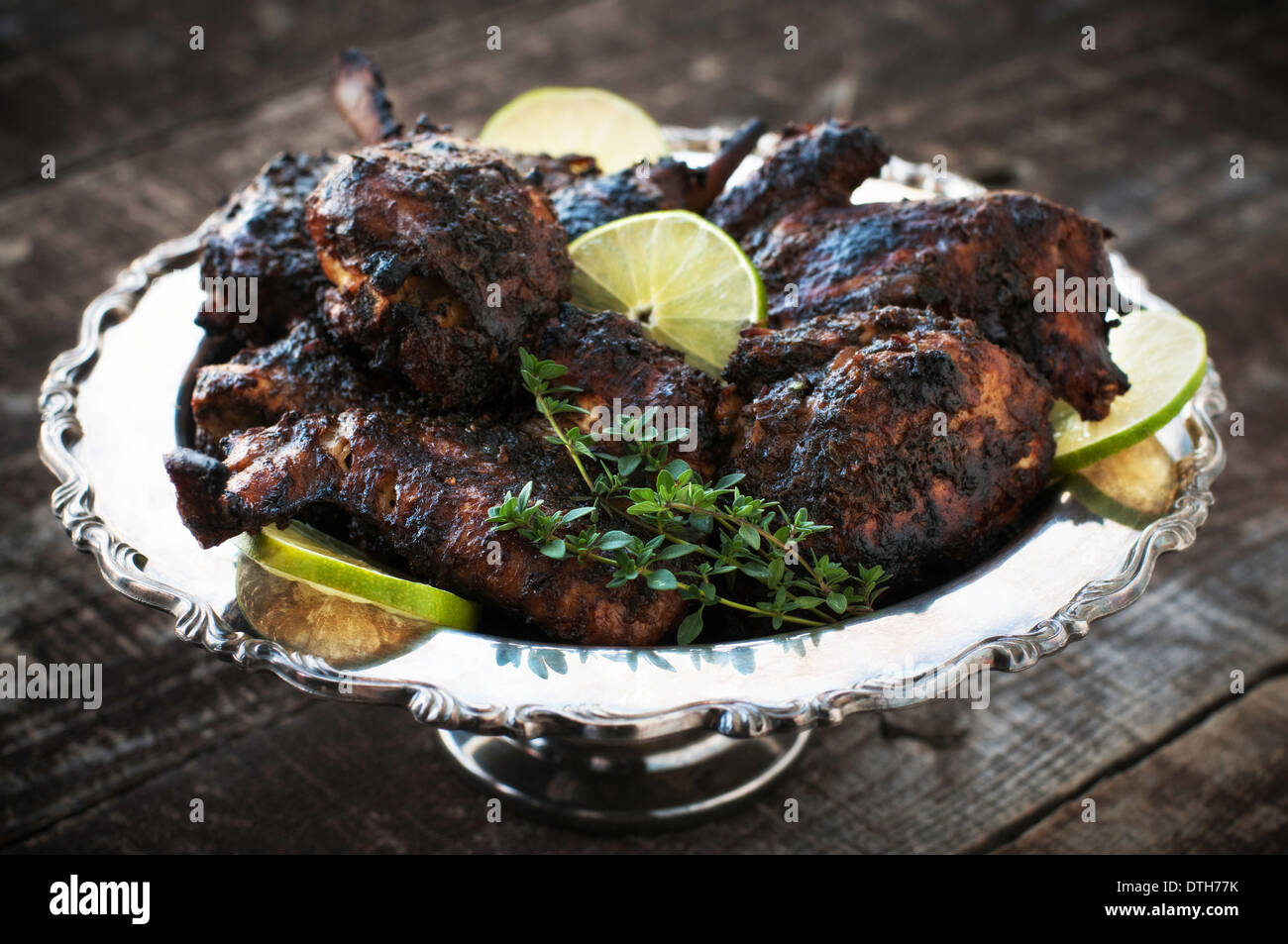 Decorativo piatto d'argento del pollo arrosto con salsa di jerk, calce e guarnire erbe Foto Stock
