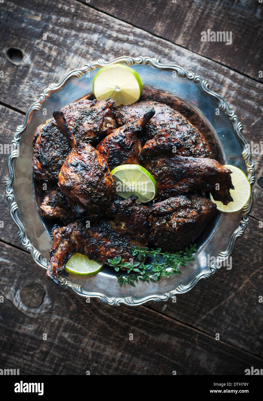Decorativo piatto d'argento del pollo arrosto con salsa di jerk, calce e guarnire erbe Foto Stock