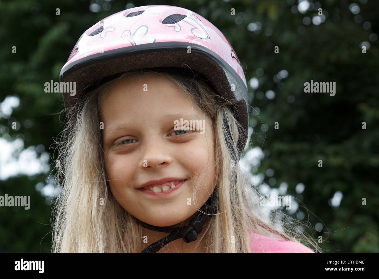 Sorridente bambina con un casco sulla sua testa Foto Stock