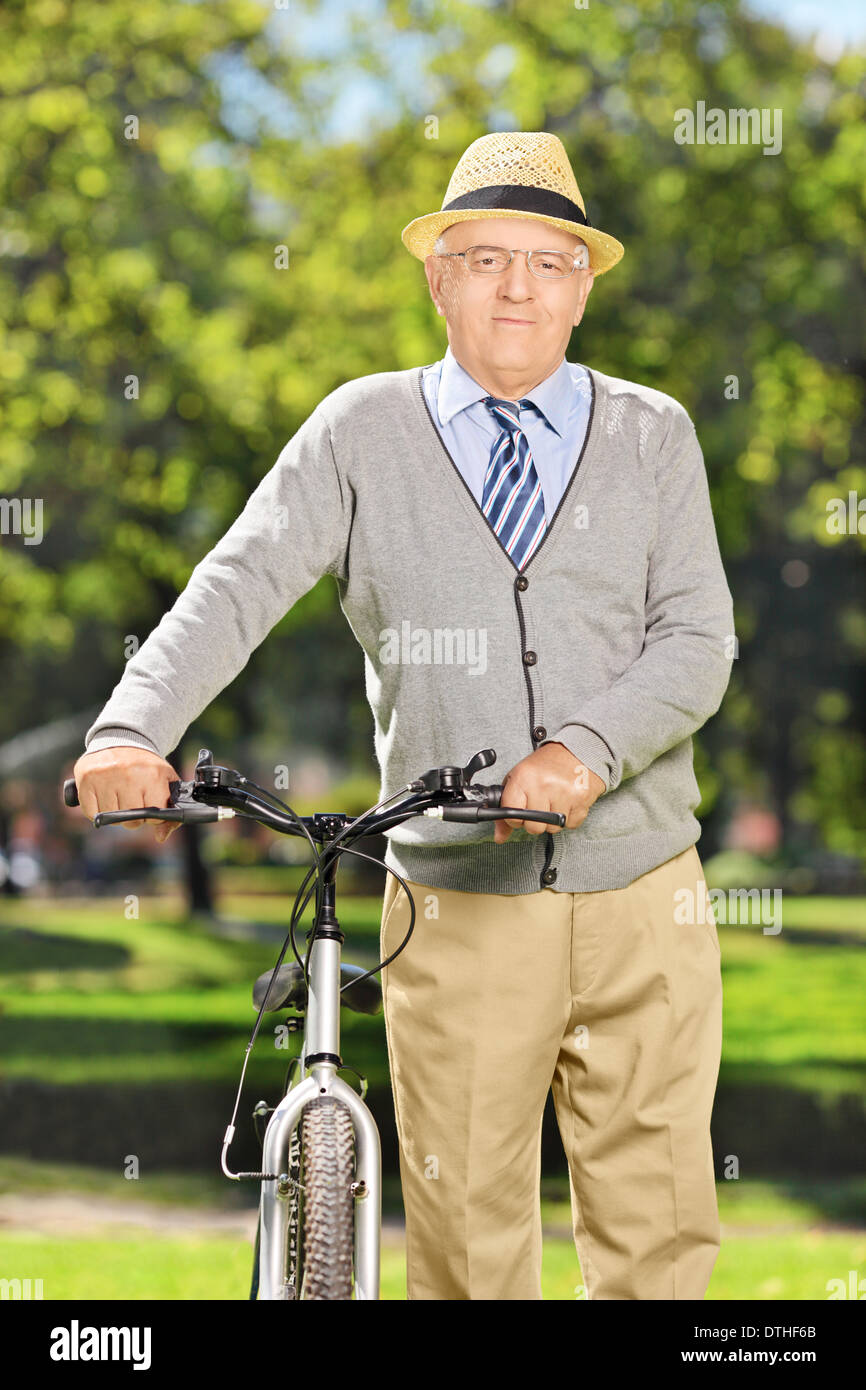 Senior gentleman spingendo una bicicletta in posizione di parcheggio Foto Stock