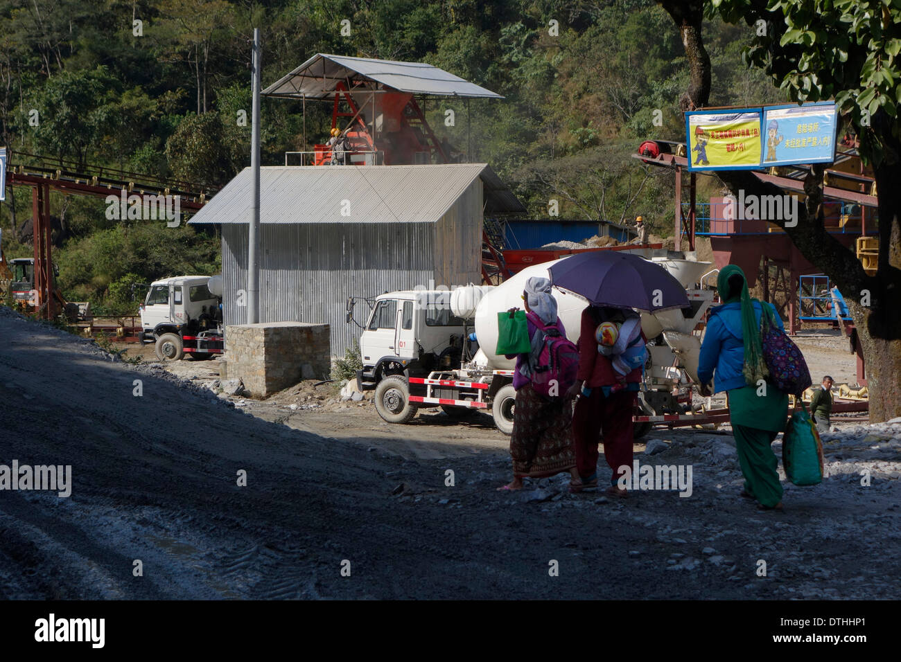 Le donne nepalesi a piedi da un nuovo impianto di cemento, parte della costruzione della tomaia Marsyangdi River progetto diga, Nepal. Foto Stock