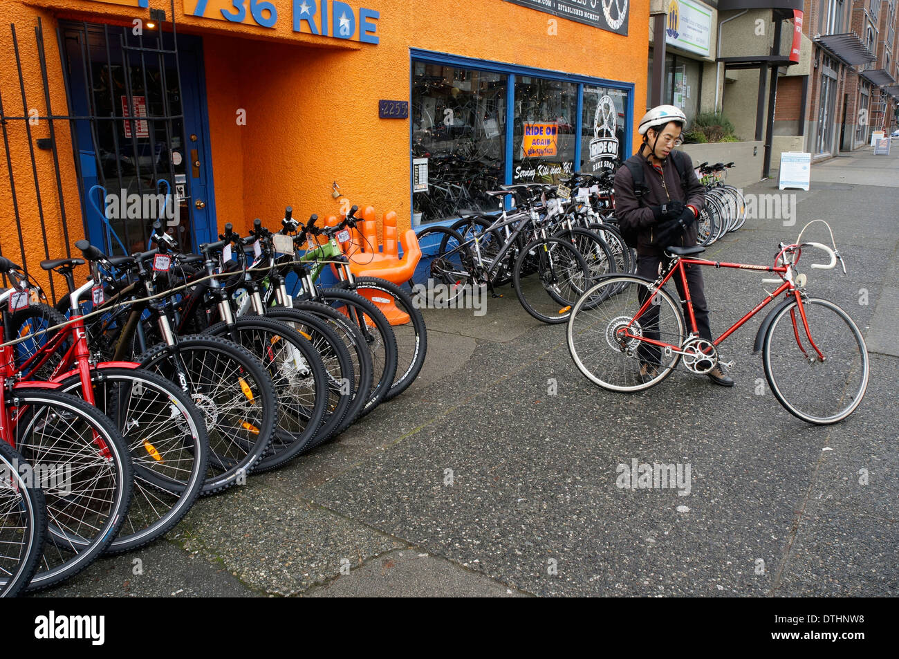 Giovani asiatici ciclista maschio outsde giro sul nuovo negozio di biciclette, Vancouver, BC, Canadai Foto Stock