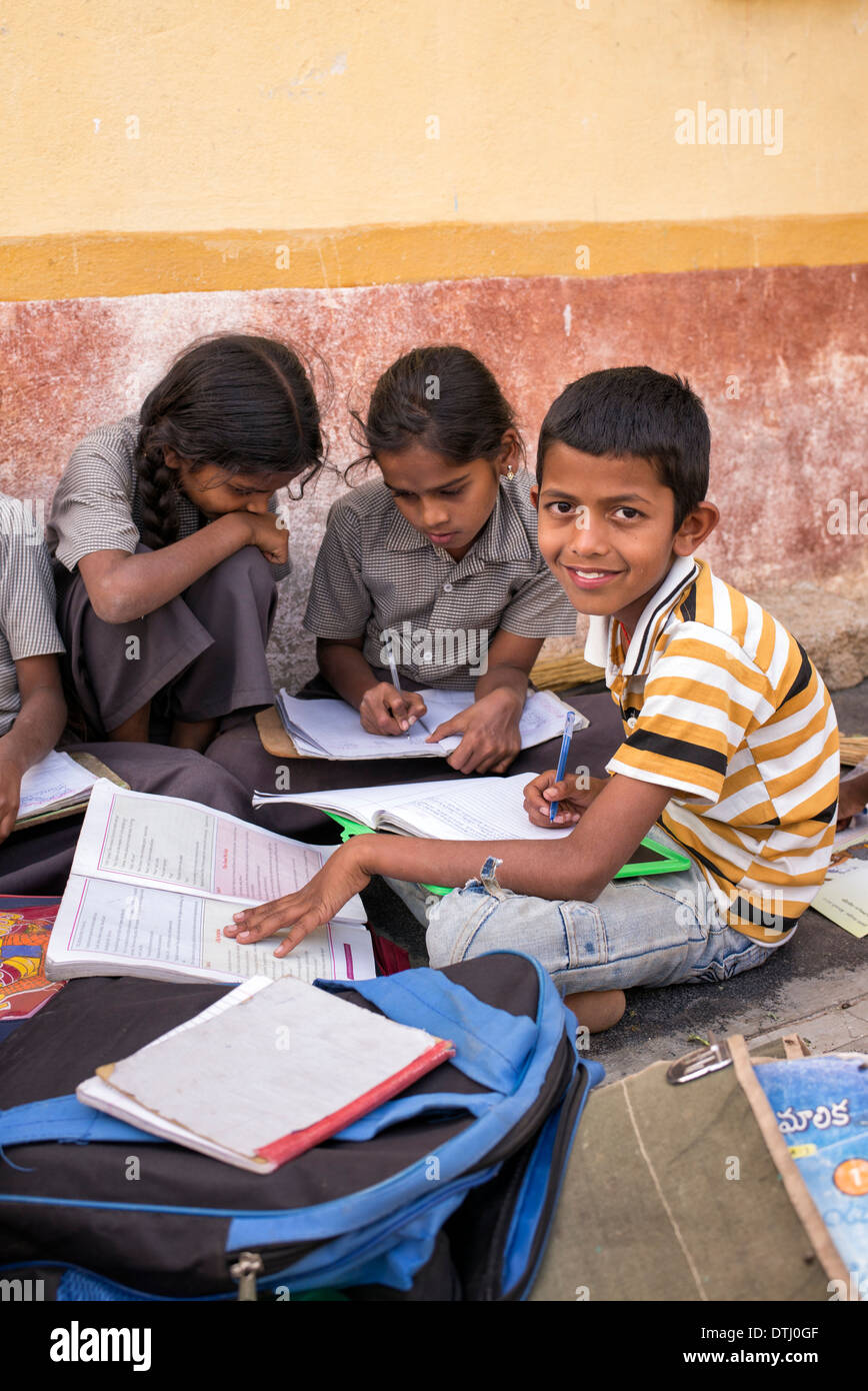 Bambini indiani scuola facendo lavorare al di fuori di una zona rurale villaggio indiano house. Andhra Pradesh, India Foto Stock