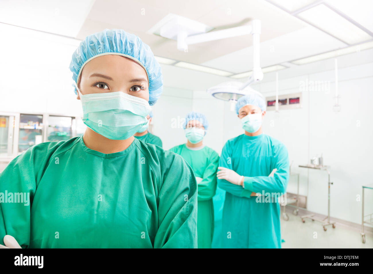 Chirurgo sorridente in posa con un team in una sala chirurgica in ospedale Foto Stock