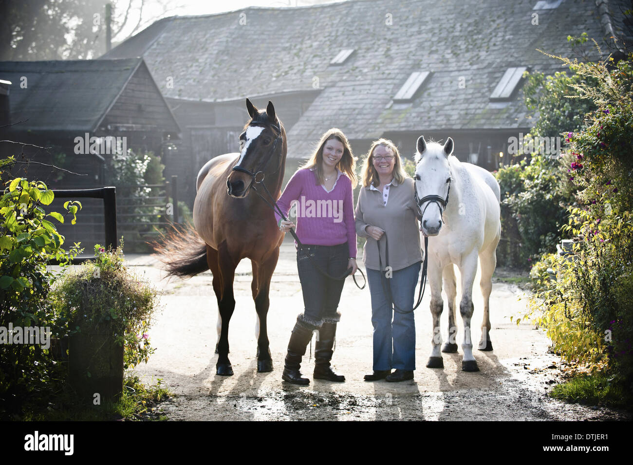 Due donne in piedi al di fuori di una stabile con due cavalli Inghilterra Foto Stock