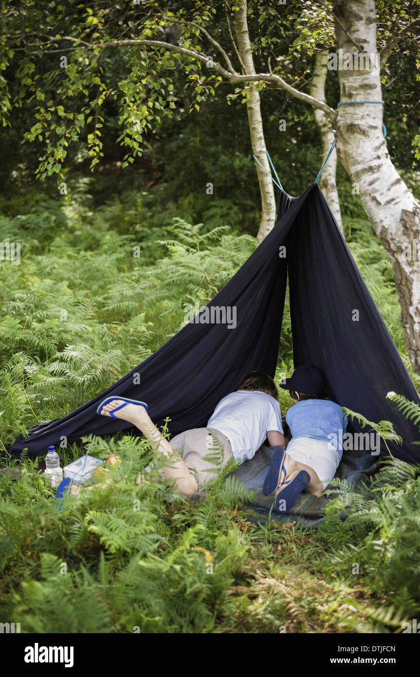 Due ragazzi nel campeggio la nuova foresta che giace sotto un riparo di tela Hampshire Inghilterra Foto Stock