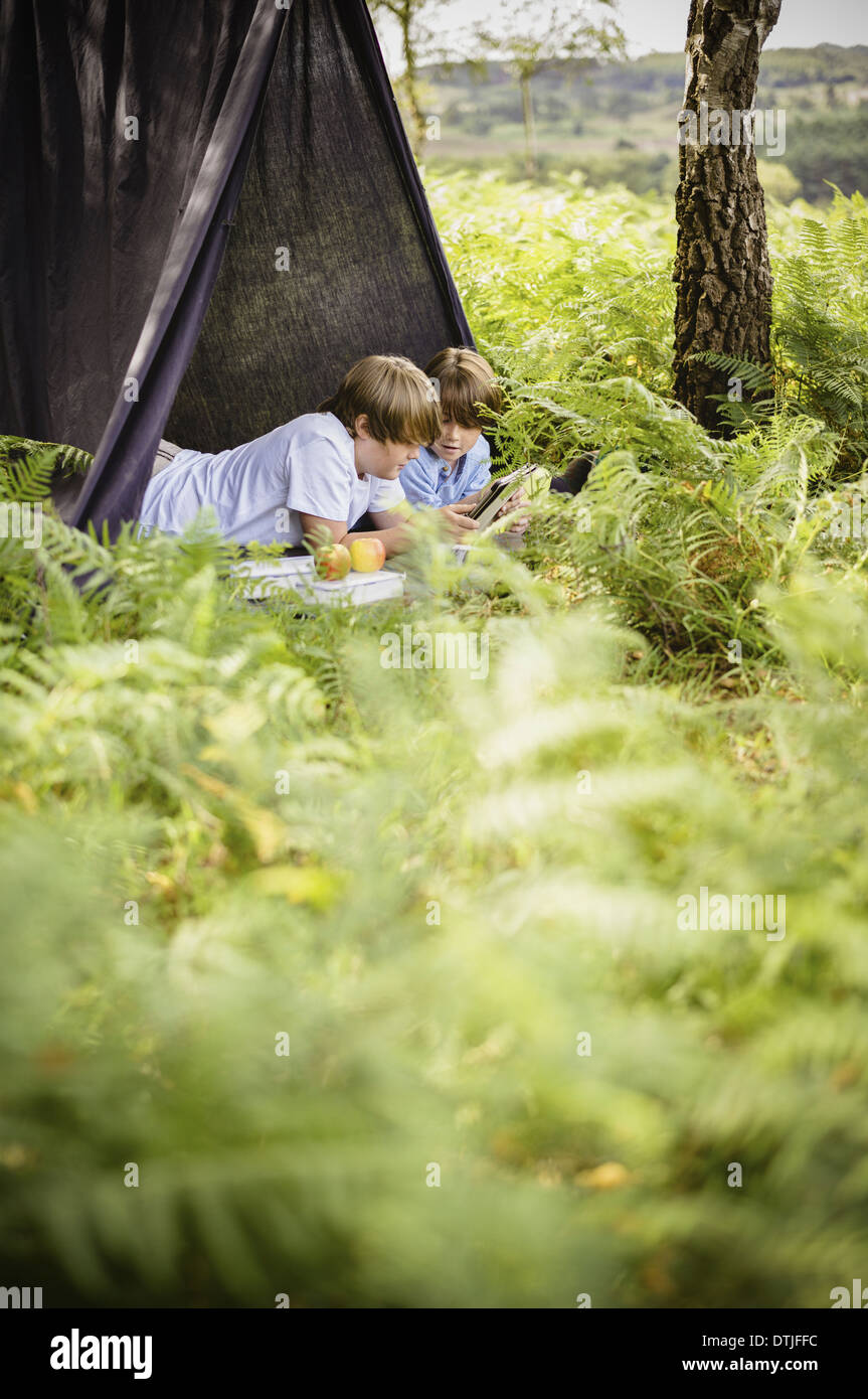 Due ragazzi nel campeggio la nuova foresta che giace sotto un riparo di tela Hampshire Inghilterra Foto Stock
